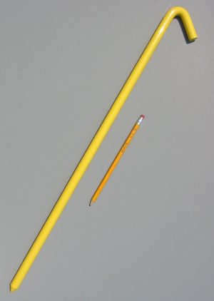 24 inch metal hook style tent stake in bright yellow and a pencil for scale
